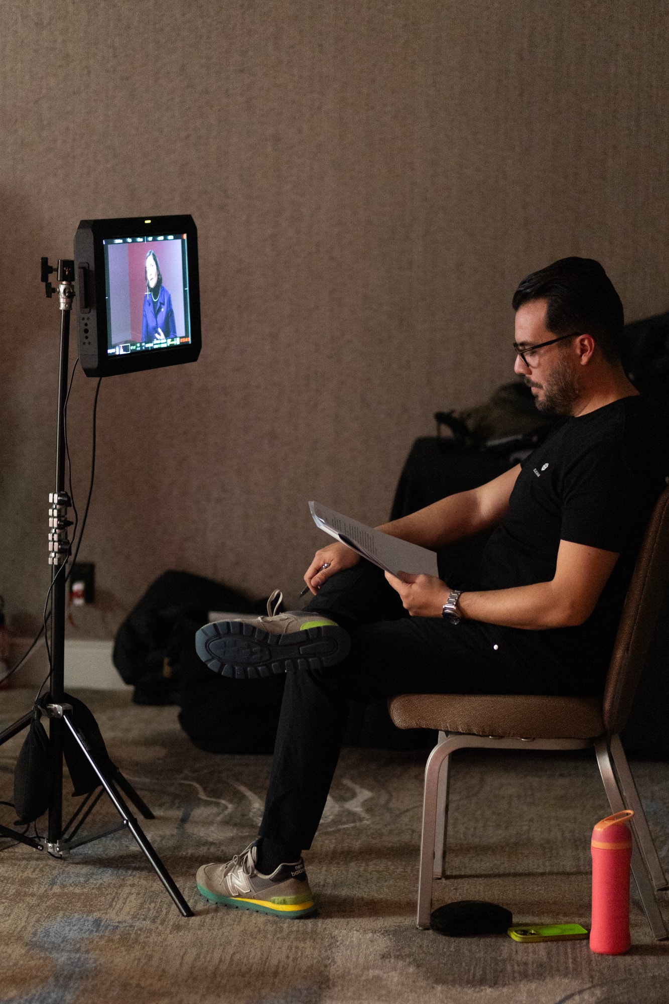 Carlos Foster reviewing notes on set, overseeing an interview
